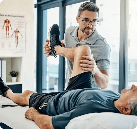Physical therapist stretching patient's leg in clinic.
